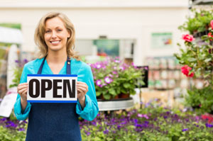 women holding open sign in front of a flowers